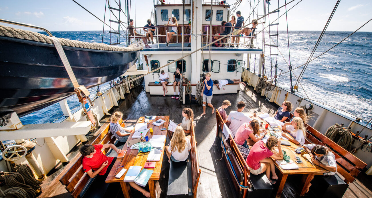 Leerlingen studeren aan dek van het zeilschip op zee